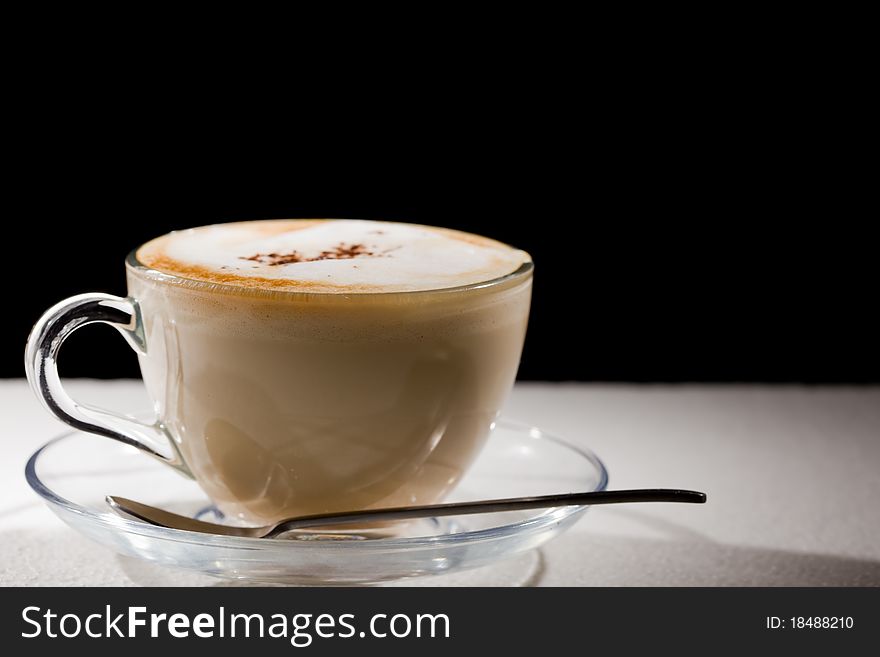 Photo of cappuccino in glass cup on white table. Photo of cappuccino in glass cup on white table