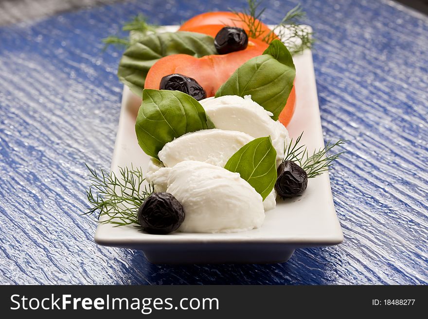 Photo of delicious tomatoe and mozzarella salad with black olives. Photo of delicious tomatoe and mozzarella salad with black olives