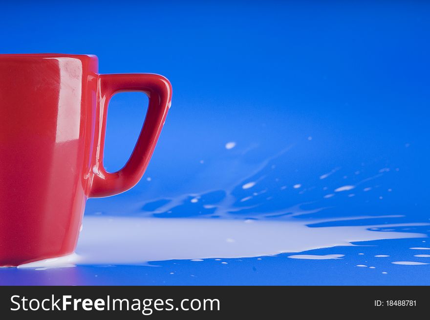 Part of red big cup with  splashing milk over blue background. Part of red big cup with  splashing milk over blue background