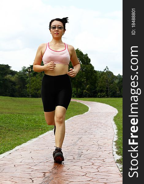 A woman jogging at a park. A woman jogging at a park