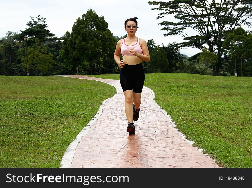 An Asian woman jogging at a park