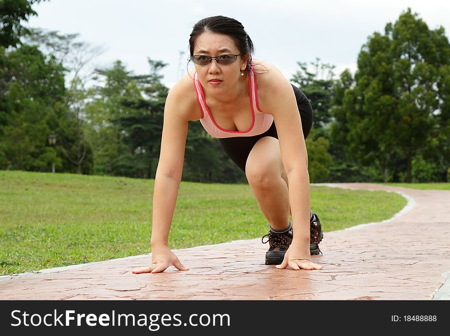 A woman in starting stance ready to run. A woman in starting stance ready to run