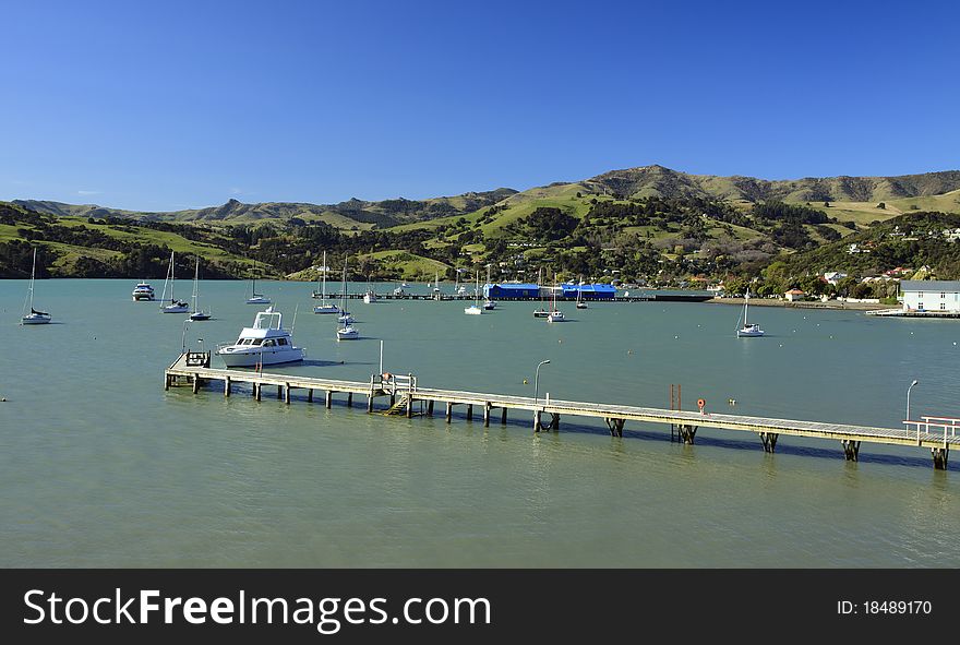 Akaroa harbour on the early morning, quite water, lazy boats and green mountains on the background. Akaroa harbour on the early morning, quite water, lazy boats and green mountains on the background
