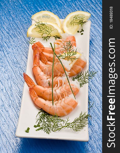 Photo of delicious raw prawns with lemon slices and onions on white plate. Photo of delicious raw prawns with lemon slices and onions on white plate