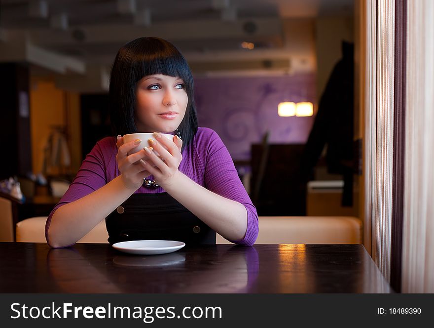 Girl hold cup of coffee in hand look in window. Girl hold cup of coffee in hand look in window