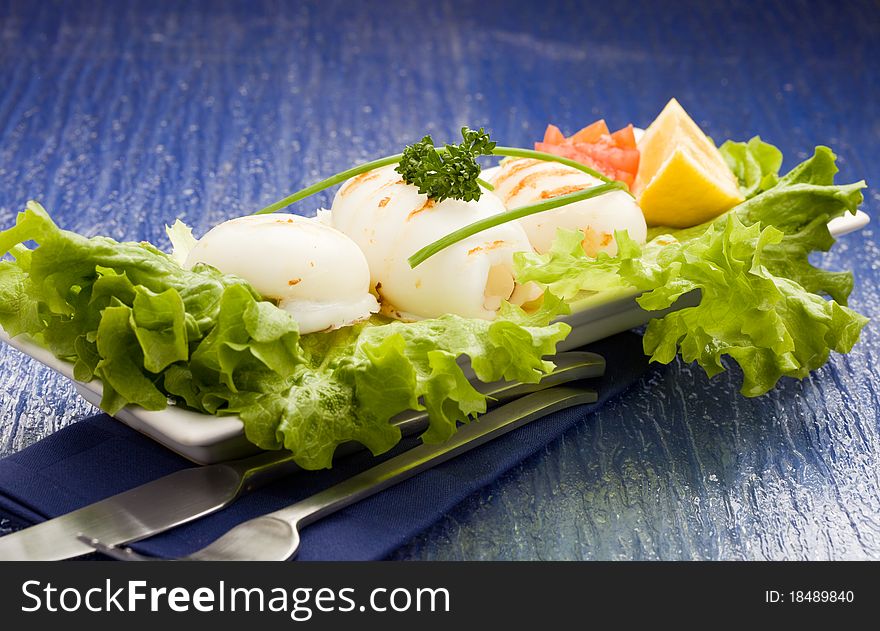 Photo of squid fish with lettuce on soft lettuce bed. Photo of squid fish with lettuce on soft lettuce bed