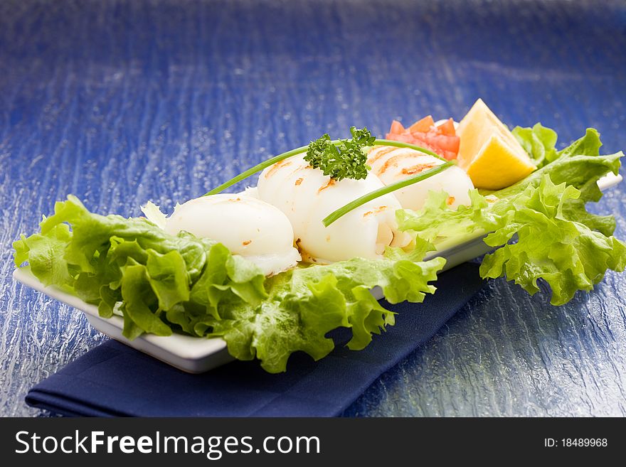 Photo of squid fish with lettuce on soft lettuce bed. Photo of squid fish with lettuce on soft lettuce bed