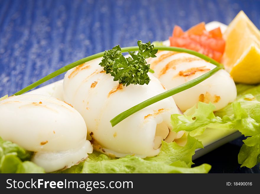 Photo of squid fish with lettuce on soft lettuce bed. Photo of squid fish with lettuce on soft lettuce bed