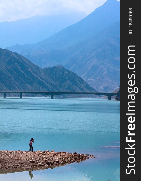 A young photographer takes photo in the upriver of Huanghe River ( The famous river in China), which locats in mountains. A young photographer takes photo in the upriver of Huanghe River ( The famous river in China), which locats in mountains.