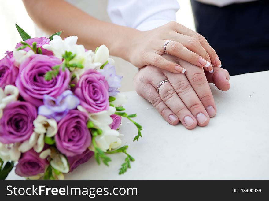 Hands of bride and groom with bouquet