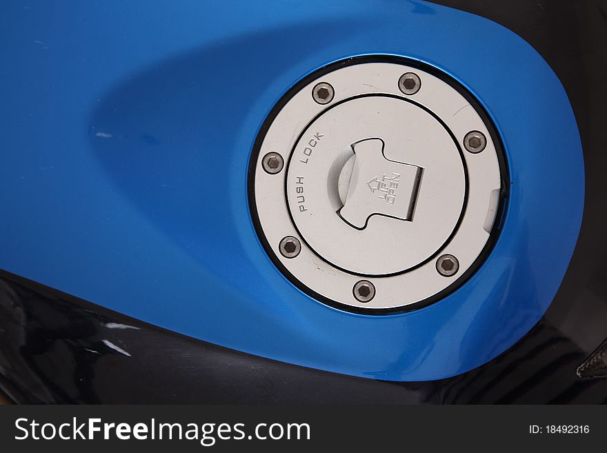 Blue and chrome fuel cap over black motorcycle. Blue and chrome fuel cap over black motorcycle