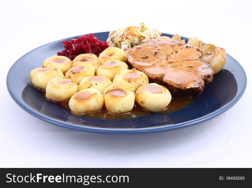 Pork steak and dumplings with side salads and baked onions