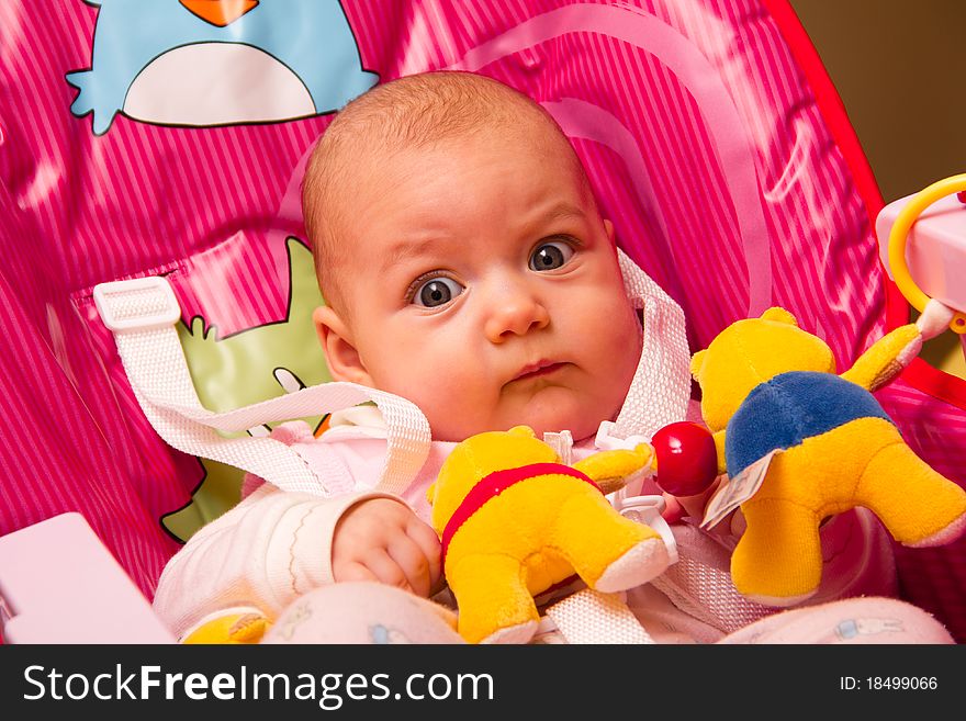 Cute baby with toys sitting on chair