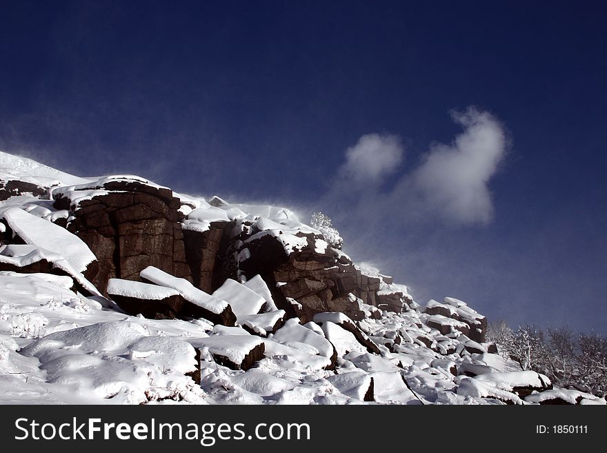 Snow being lifted by the wind from the top of rocks. Snow being lifted by the wind from the top of rocks