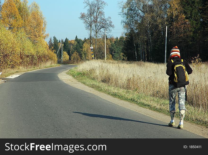 Young girl walking alone through the autumn park with knapsack