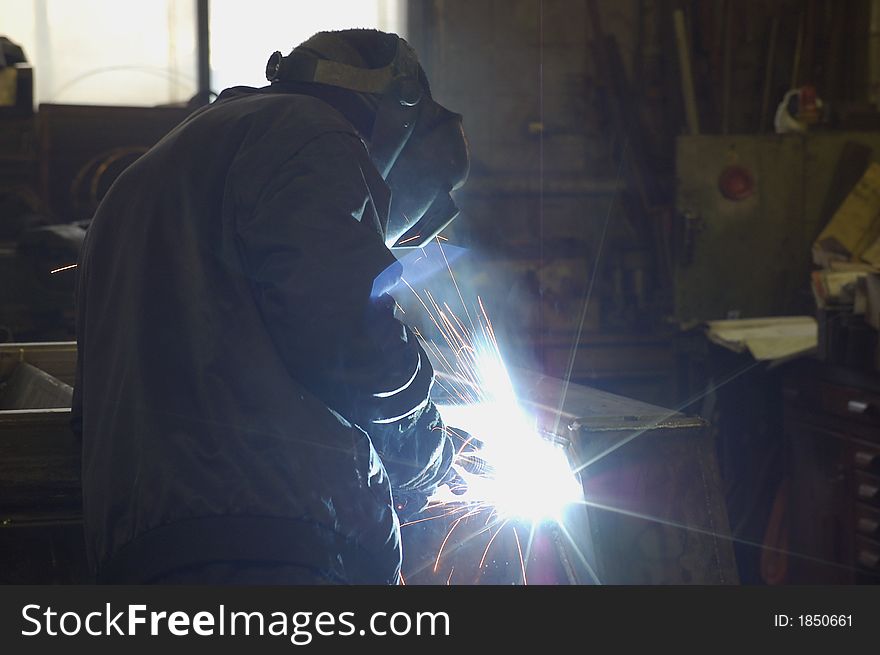 Welder at his workplace. Welding a metal construction. Welder at his workplace. Welding a metal construction