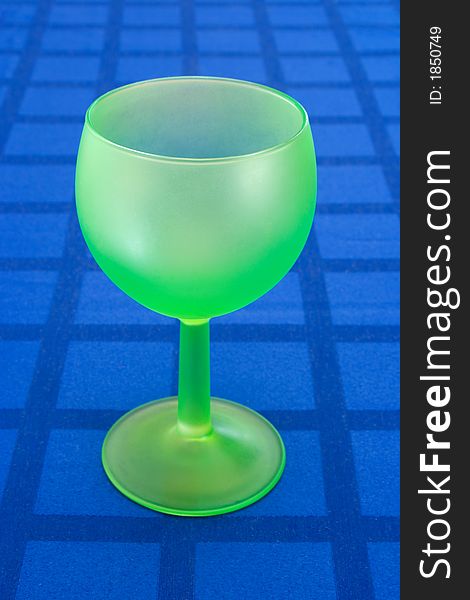 Stylish green wineglass on blue tablecloth