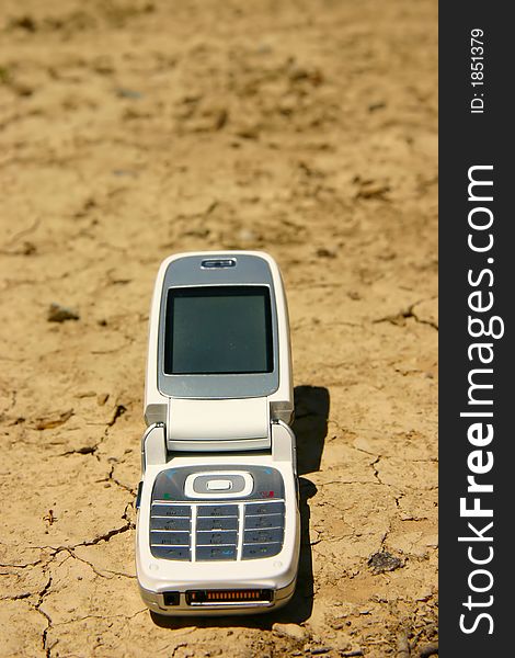 White mobile cell phone in a dry, cracked river bed. White mobile cell phone in a dry, cracked river bed