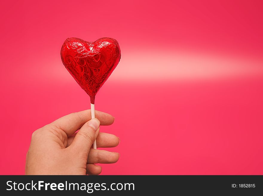 Woman holding a heart lolly in her hand. Woman holding a heart lolly in her hand