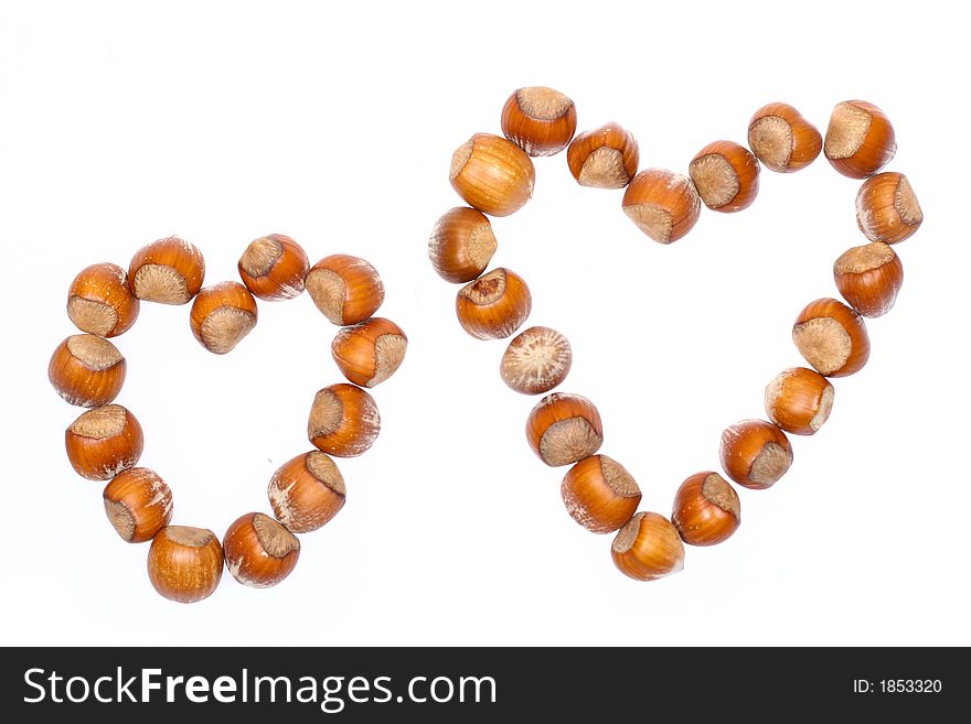 Closeup for little hazelnuts in heart shape isolated on white background