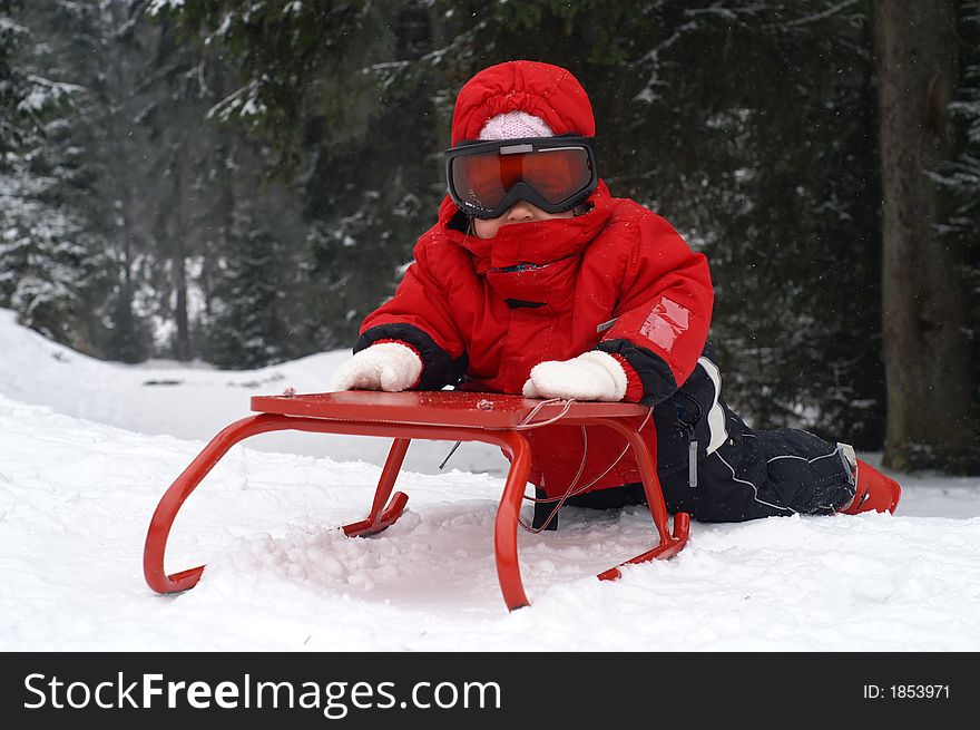 Two and a half year old girl playing with a red sledge. Two and a half year old girl playing with a red sledge.