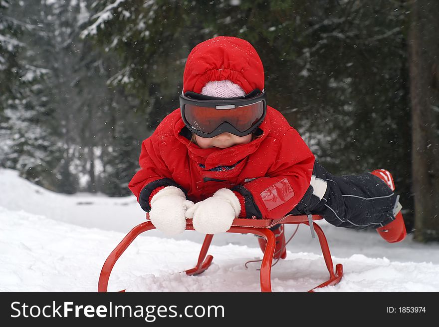 Two and a half year old girl playing with a red sledge. Two and a half year old girl playing with a red sledge.