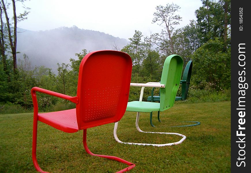 A lovely view of the mountains and fog with colorful chairs in the foreground. A lovely view of the mountains and fog with colorful chairs in the foreground.