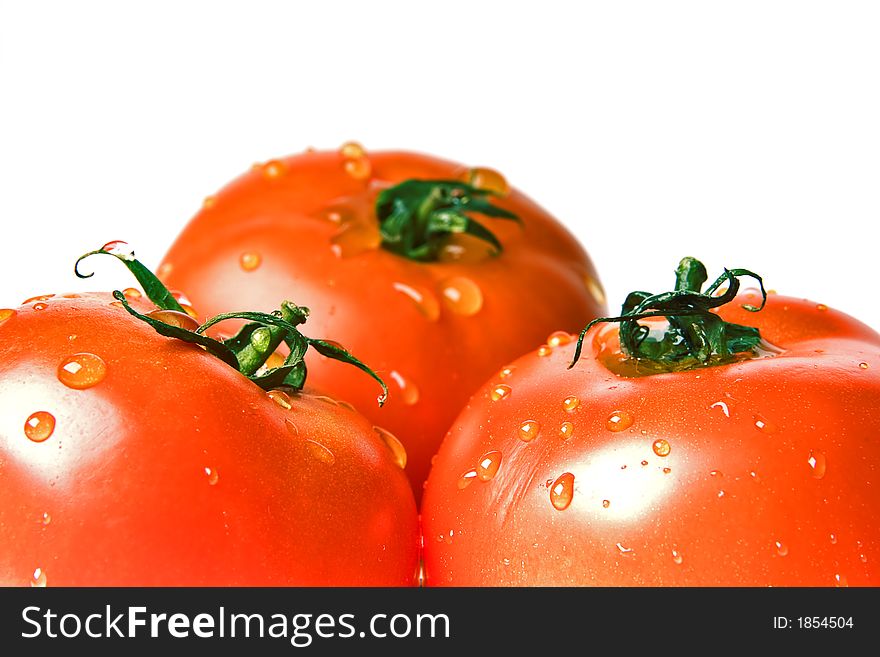 Three ripe tomatoes covered bright drops on a white background