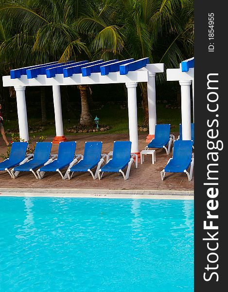 Blue lounge chairs around a tropical blue pool setting. Blue lounge chairs around a tropical blue pool setting