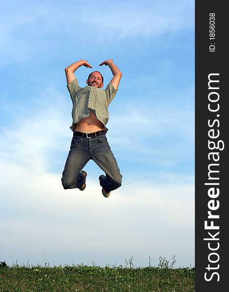 A man jumping over grass with a blue sky behind him