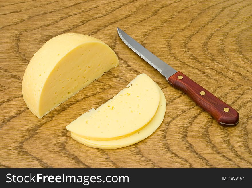 Cheese, slices and knife on wooden table