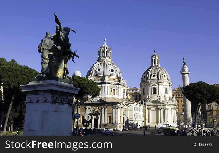 Monumental domes of the church on piazza Venezia with forum column and sculpture of the national monument