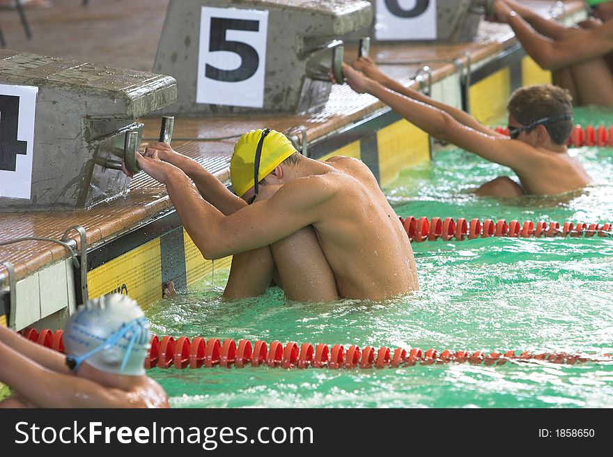 Young men at start of backstroke event hanging on to starting blocks. Young men at start of backstroke event hanging on to starting blocks