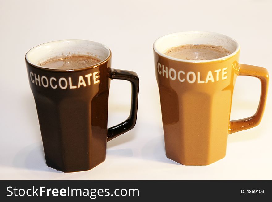 Two cups hot chocolate milk light background