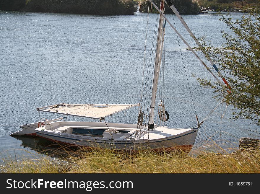 Traditional Egyptian sailing boat known as Felucca anchored at an island in Nile river. Traditional Egyptian sailing boat known as Felucca anchored at an island in Nile river.