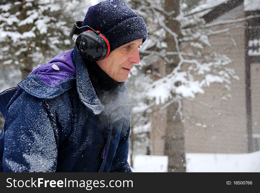 Senior man snow blowing outside after heavy snowfall