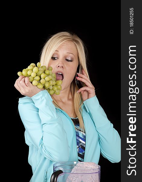 A woman is holding grapes and talking on the phone. A woman is holding grapes and talking on the phone.