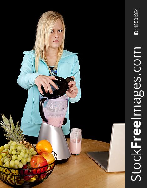 A woman is looking mad and dropping her cell phone into a blender. A woman is looking mad and dropping her cell phone into a blender.