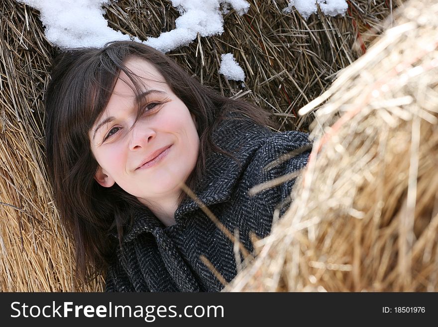 Beautiful brunette female leaning against hay bales