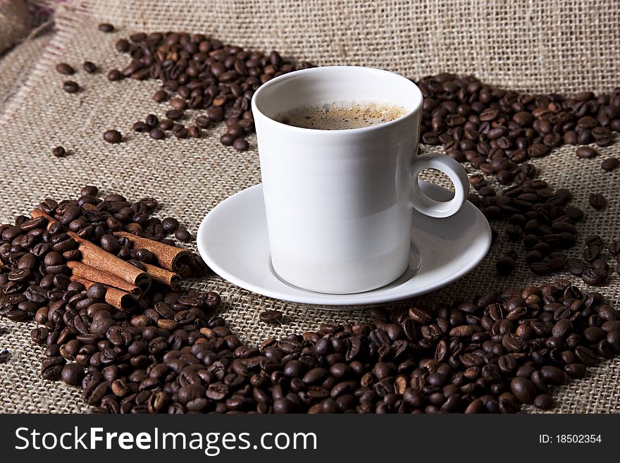 Cup of coffee with cinnamon and coffee grains