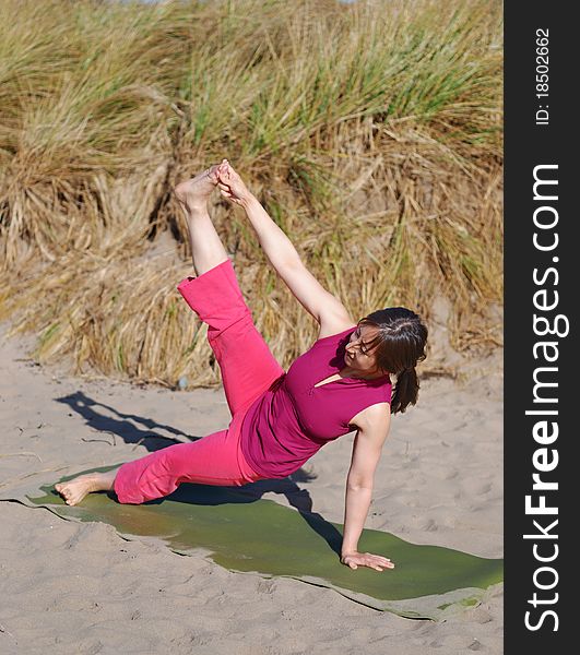 A young woman performs yoga on a beach. A young woman performs yoga on a beach.