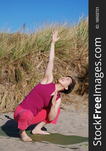 A young woman performs yoga on a beach. A young woman performs yoga on a beach.