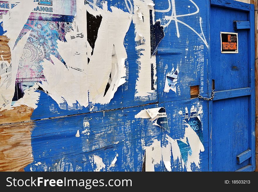 Blue wall with layers of ripped posters and a no trespassing sign on the door. Blue wall with layers of ripped posters and a no trespassing sign on the door