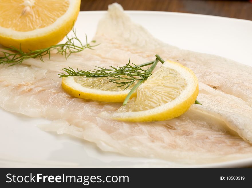 Photo of tasty smoked sea bass fish with lemon slices and fennel on it. Photo of tasty smoked sea bass fish with lemon slices and fennel on it