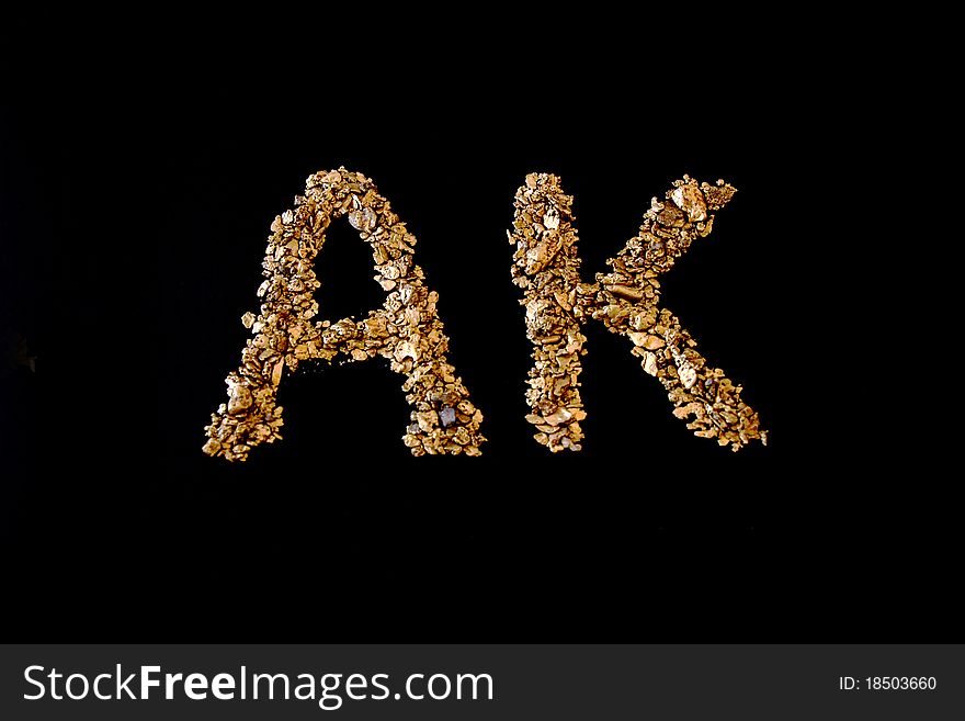 AK spelt with real Alaskan Gold on a black background from Nome. AK spelt with real Alaskan Gold on a black background from Nome