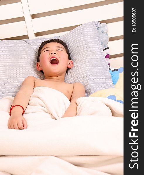 Picture of a little chinese boy laughing happily while lying on the bed. Picture of a little chinese boy laughing happily while lying on the bed