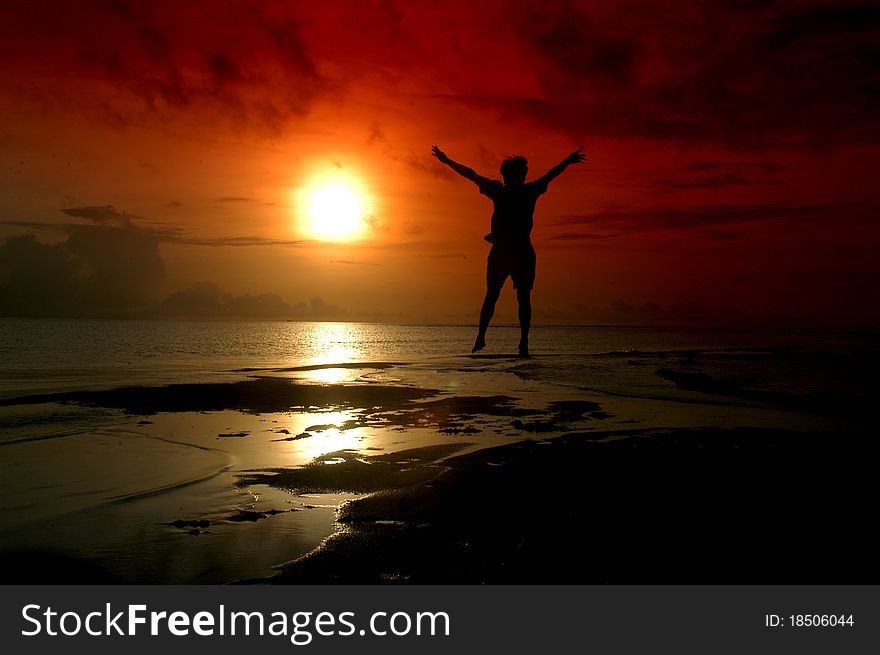 Silhouette of a man jumping toward sunrise