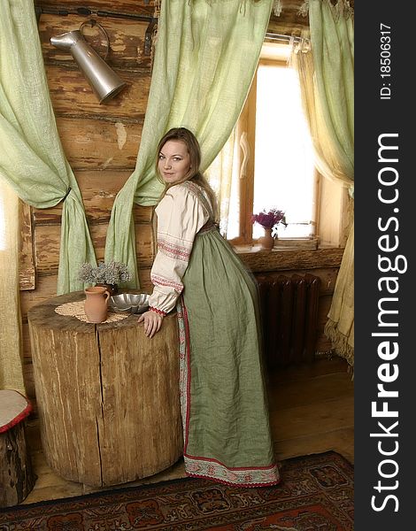 A young Russian woman in traditional Russian clothes. Interior of Russian country house. A young Russian woman in traditional Russian clothes. Interior of Russian country house.