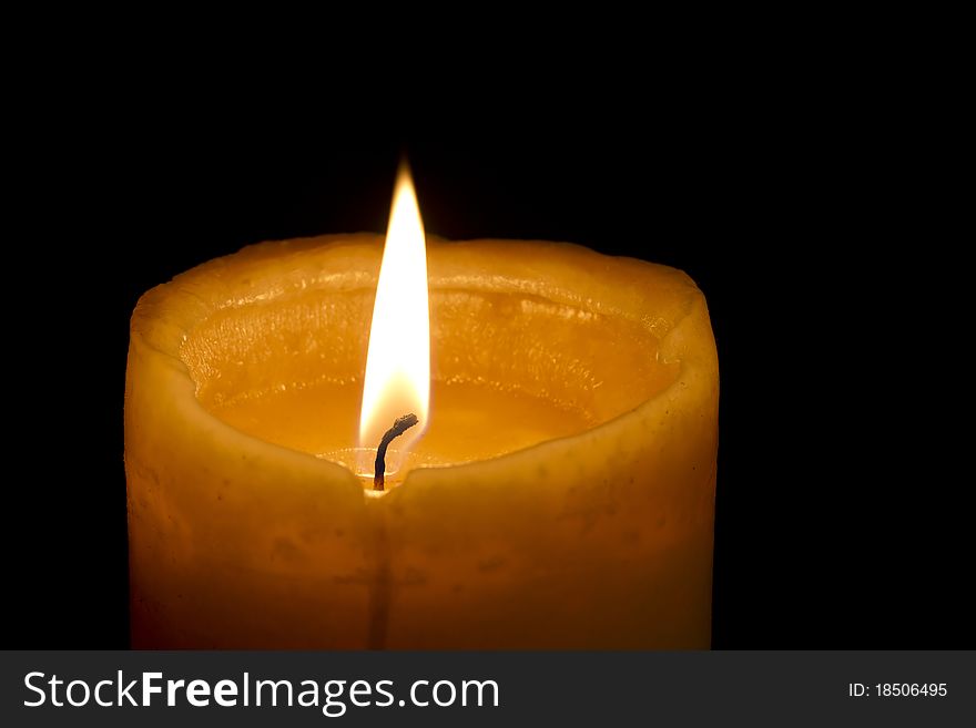 Single glowing orange candle on black background. Single glowing orange candle on black background