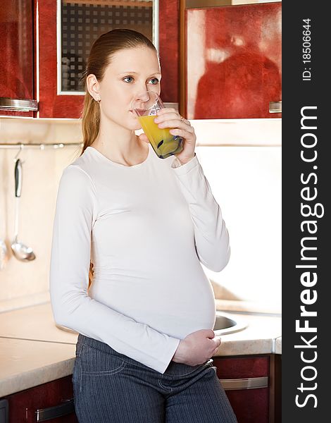 Pregnant woman in kitchen with glass of juice
